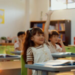A teacher explains the new ABC song to young students, highlighting the updated phrasing for improved literacy skills.