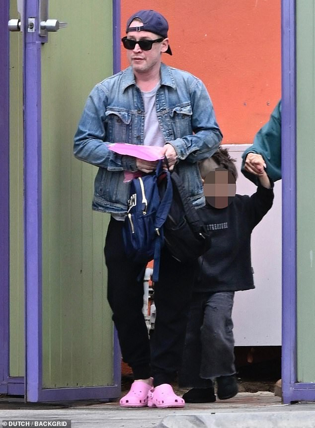 Macaulay Culkin's casual outfit during a family outing in Los Angeles, featuring a denim jacket, joggers, pink Crocs and a backwards hat